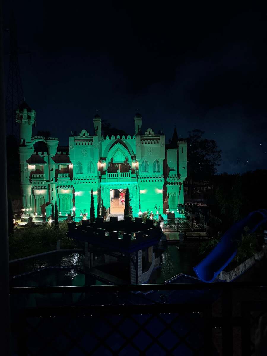 The castle illuminated at night above the pool